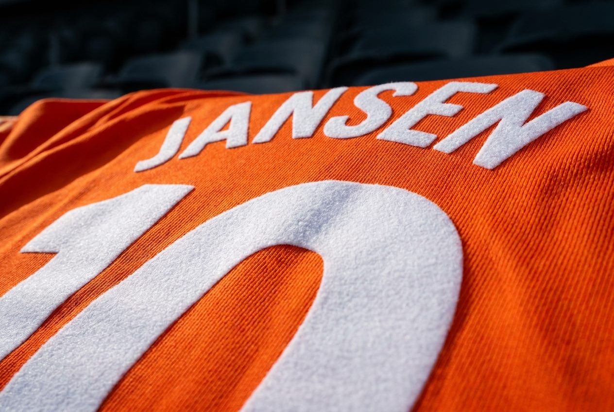 Detail van officiële naam- en nummerbedrukking op een oranje voetbalshirt